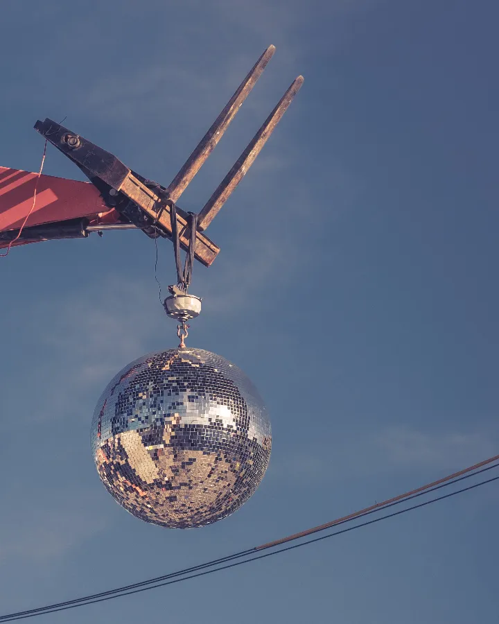 Een discobal die door een verreiker omhoog wordt getild, tegen een blauwe lucht